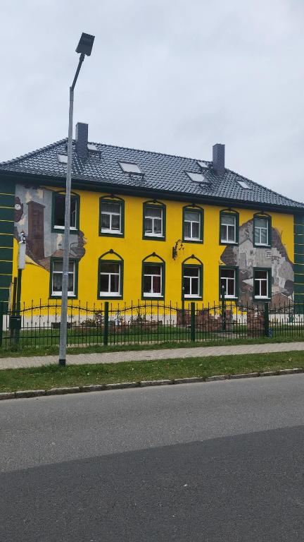 ein gelbes Gebäude mit einem Gemälde auf der Seite in der Unterkunft JaNettes Gästehaus in Bad Doberan