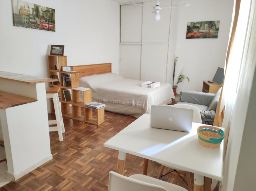 um pequeno quarto com uma cama e uma mesa com um computador portátil em Vuelta de Obligado Apartment em Buenos Aires