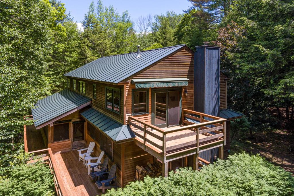 een hut in het bos met een terras en stoelen bij Coolidge Drive Retreat in Quechee