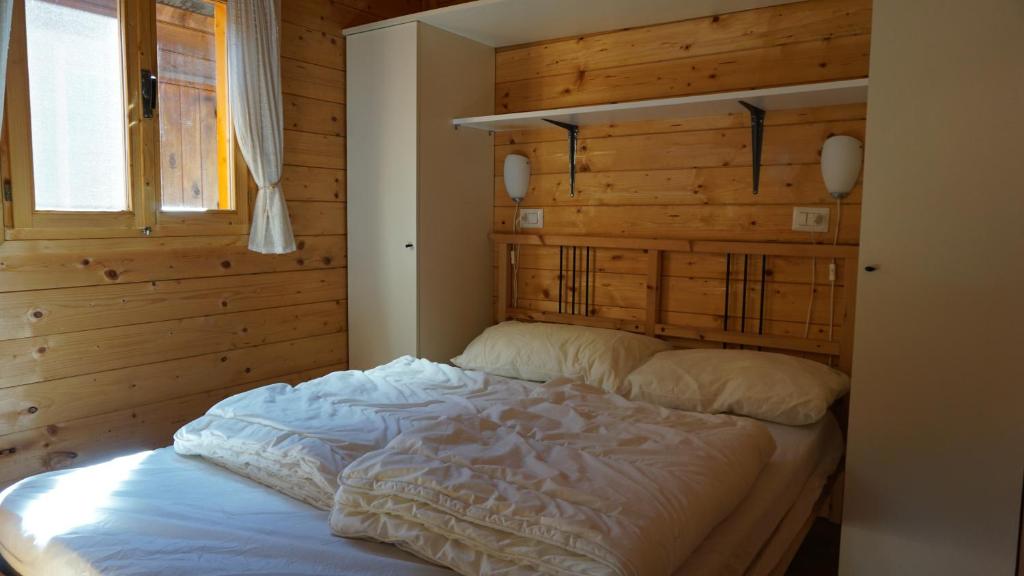 a bed in a bedroom with a wooden wall at Vakantiehuis Porlezza in Porlezza