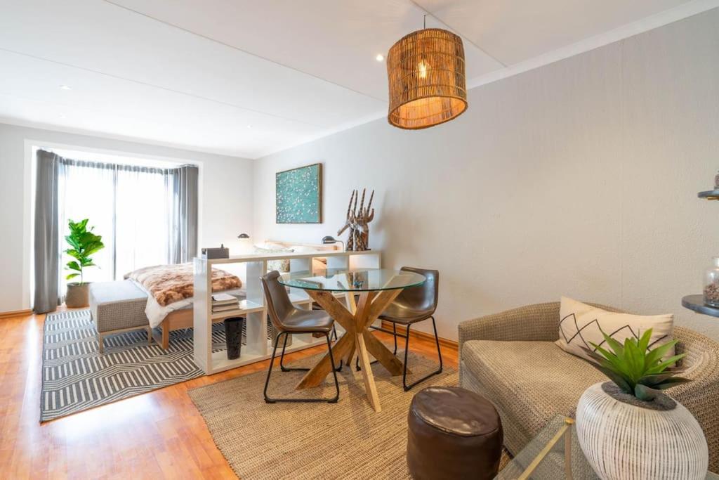 uma sala de estar com uma mesa e um sofá em Modern apartment in culturally vibrant Melville 22 em Joanesburgo