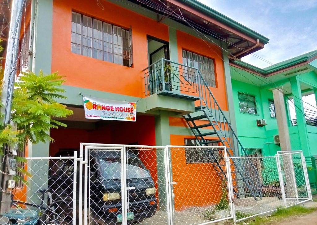 a colorful house with a fence in front of it at Estrelle Orange House - Backpackers Hub in Puerto Princesa City