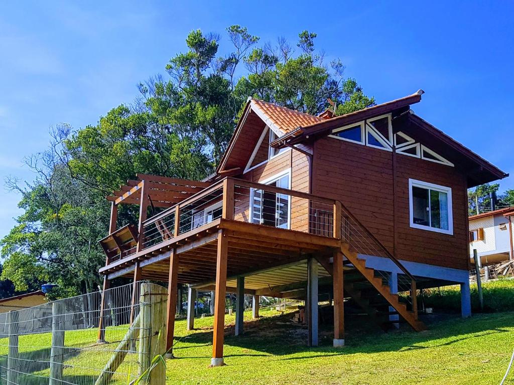 a house with a wrap around deck on the grass at Moradas do Maneca in Imbituba