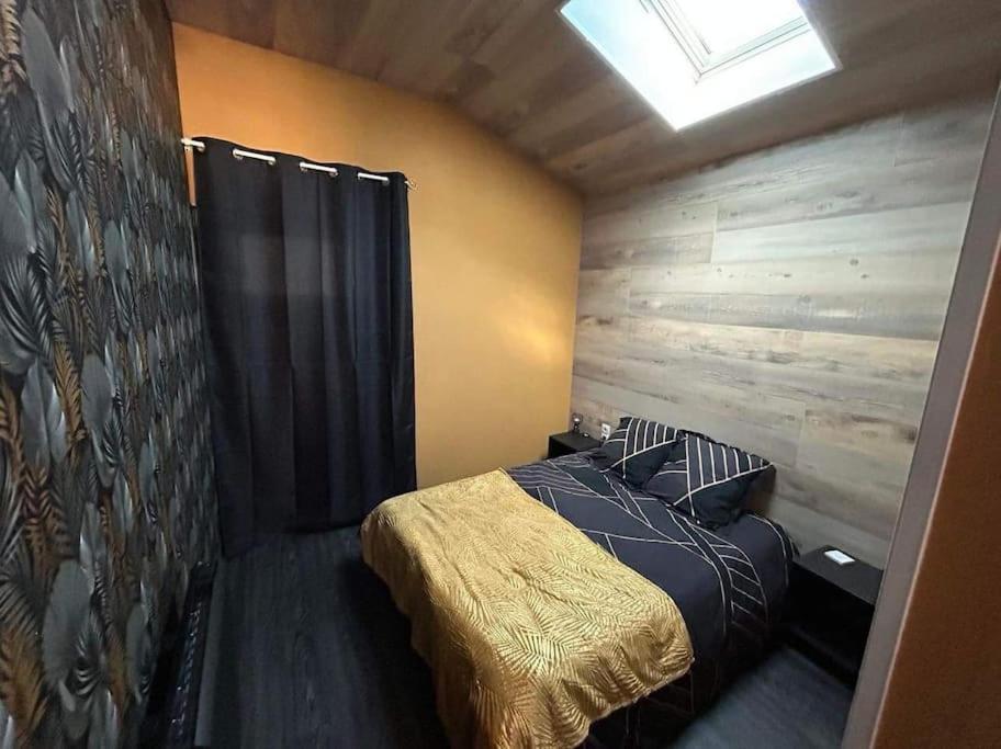 een slaapkamer met een bed met een houten muur bij Appartement très agréable proche tous commerces in Meschers-sur-Gironde