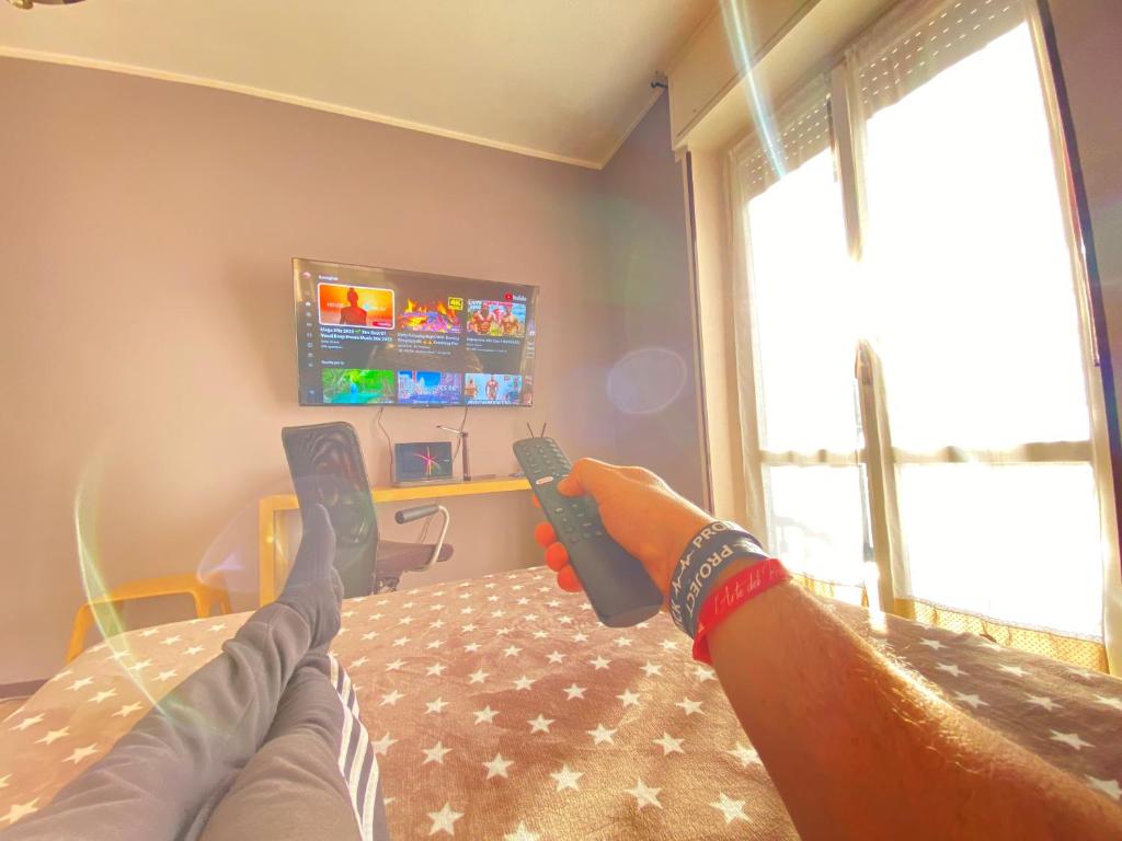 a person laying on a bed with their feet on a television at Milano relax family house in Brugherio