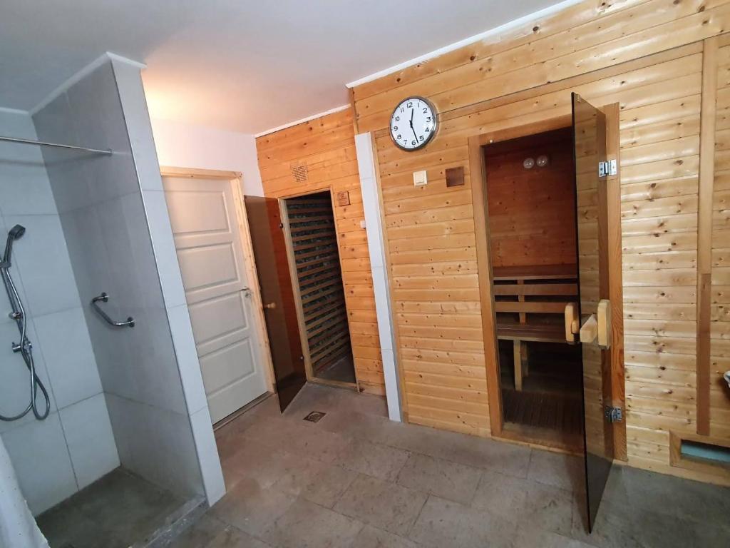 a bathroom with a clock on a wooden wall at Villa Harmónia Panzió in Visegrád