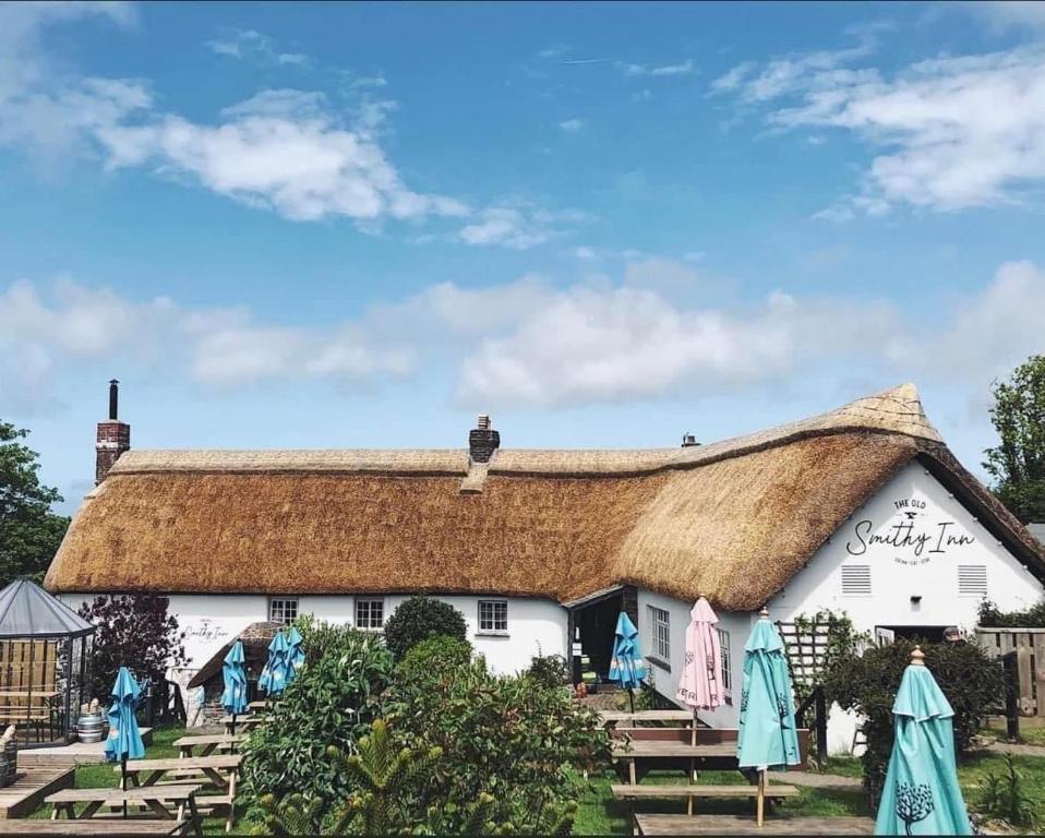 a white cottage with a thatched roof at The Old Smithy Inn in Welcombe