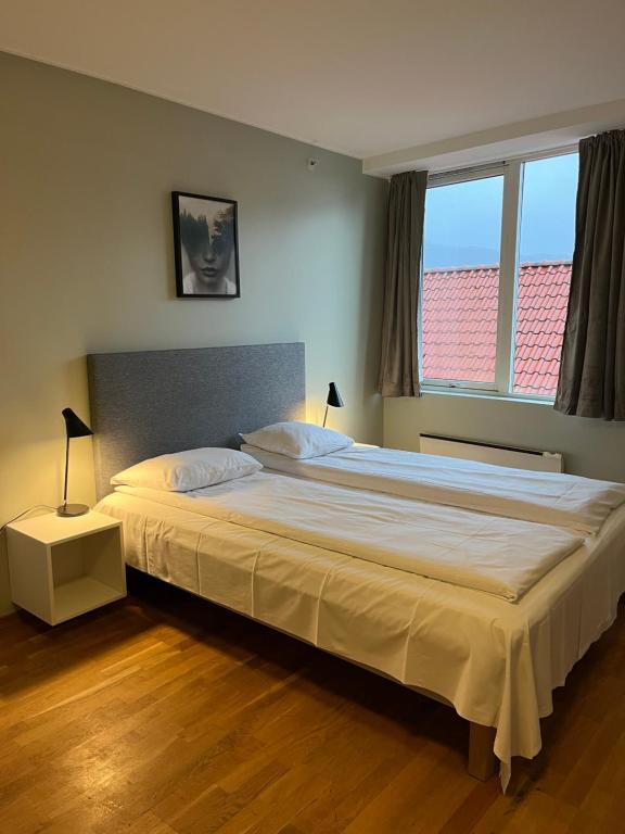 a bedroom with a large white bed with two windows at City Hostel Bergen in Bergen