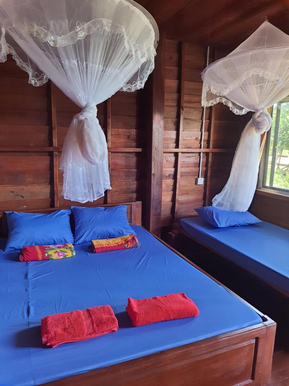 1 dormitorio con 2 camas con cortinas y almohadas rojas en Happy bungalow & trekking, en Banlung