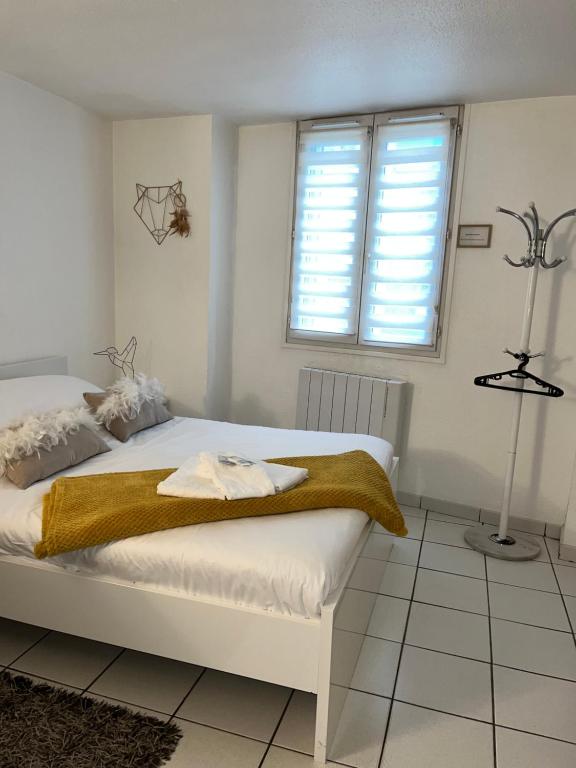 ein weißes Schlafzimmer mit einem Bett und einem Fenster in der Unterkunft Studio Porte du Croux in Nevers
