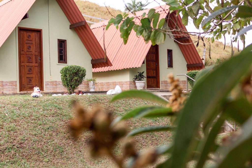 una casa con techo rojo y algunos animales en el patio en Pousada e Pesque e Pague Vista Alegre, en Paty do Alferes