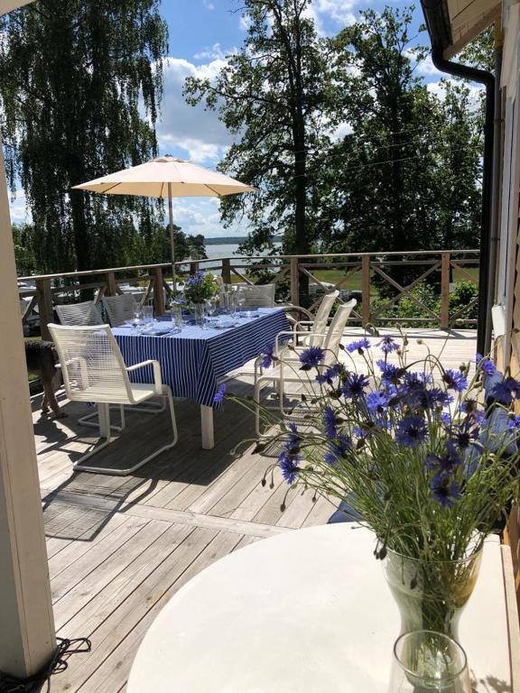 una mesa y sillas en una terraza con un jarrón de flores en Ferienhaus am Vänern mit Seeblick en Mariestad