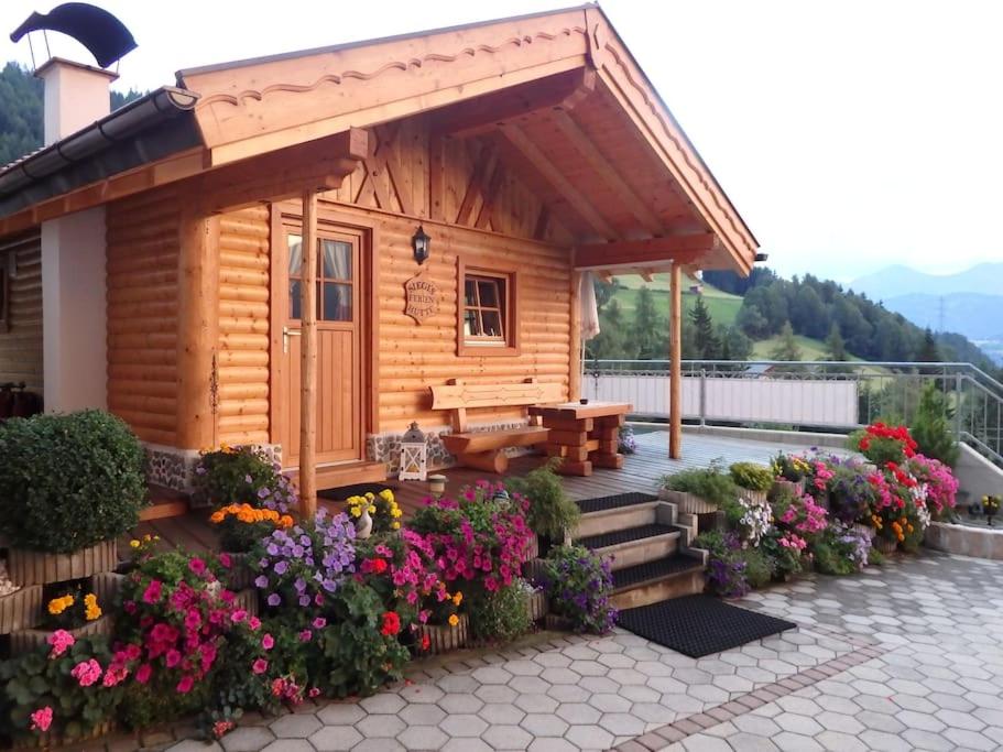 a small wooden cabin with a bench and flowers at Siegi's Ferienhütte in Fendels