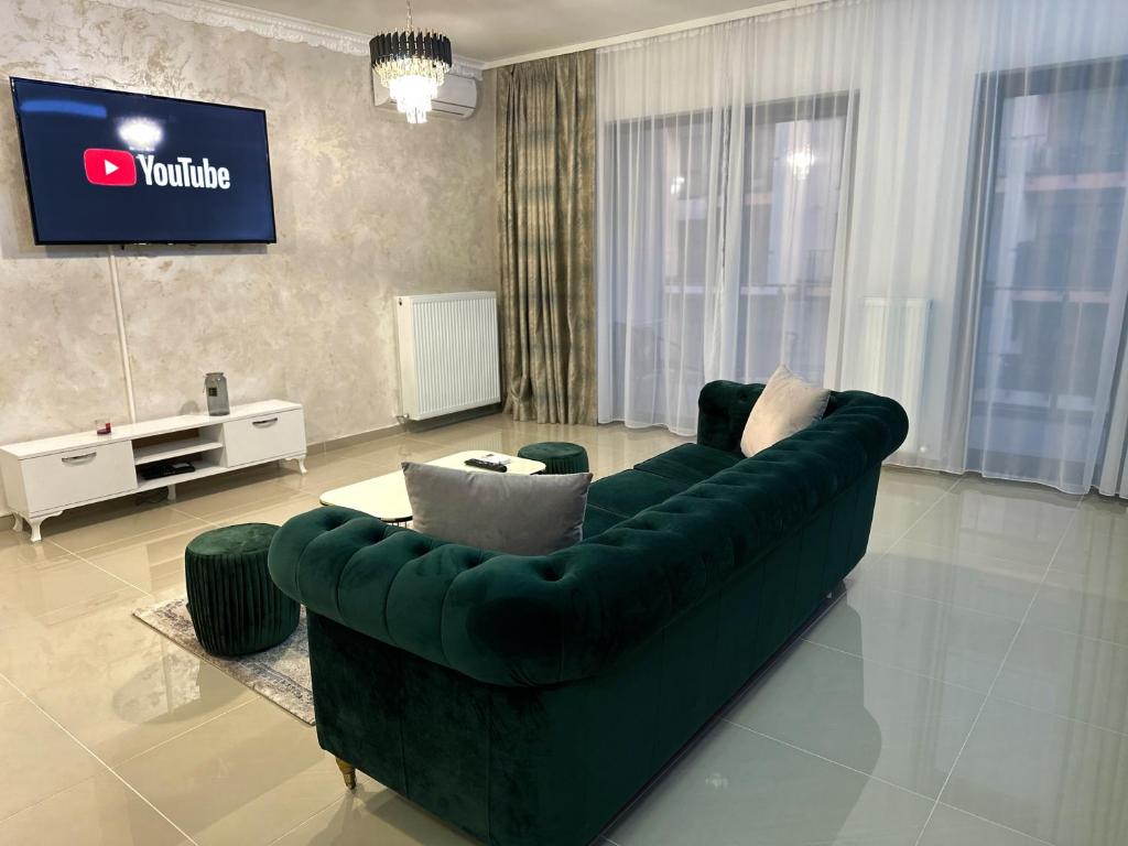 a living room with a green couch and a tv at Mrs Smart Luxury Apartament in Ploieşti
