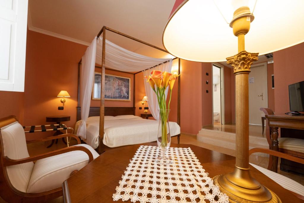 - une chambre avec un lit et une table ornée d'un vase de fleurs dans l'établissement Hotel Ristorante Vecchia Vibo, à Vibo Valentia