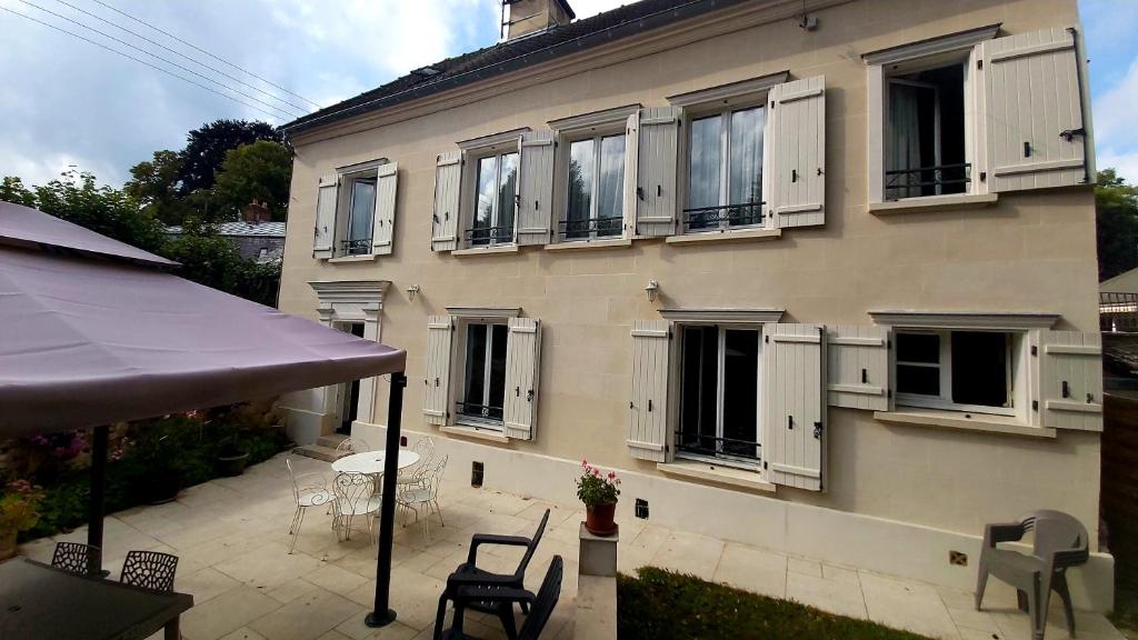 un bâtiment avec une table et des chaises devant lui dans l'établissement La Pierre Précieuse, à Château-Thierry