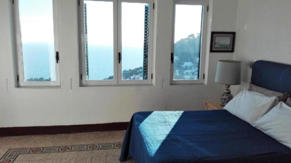 una camera da letto con finestre e un letto con una coperta blu di Sunshine a Capri