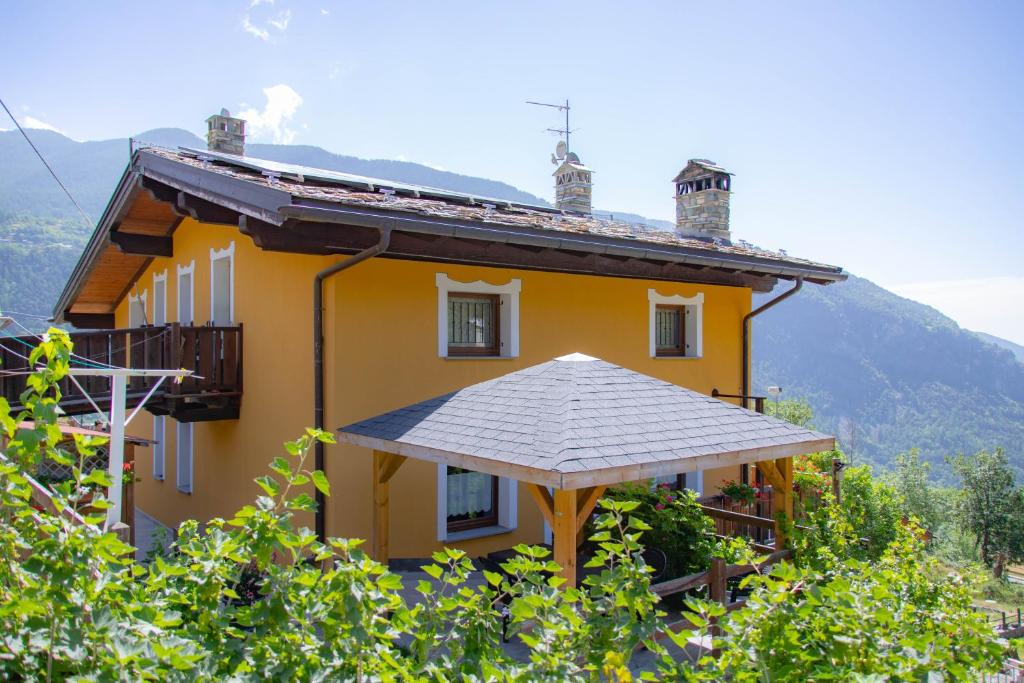una casa amarilla con techo en una colina en Lo Verdzé di Torgnon en Torgnon