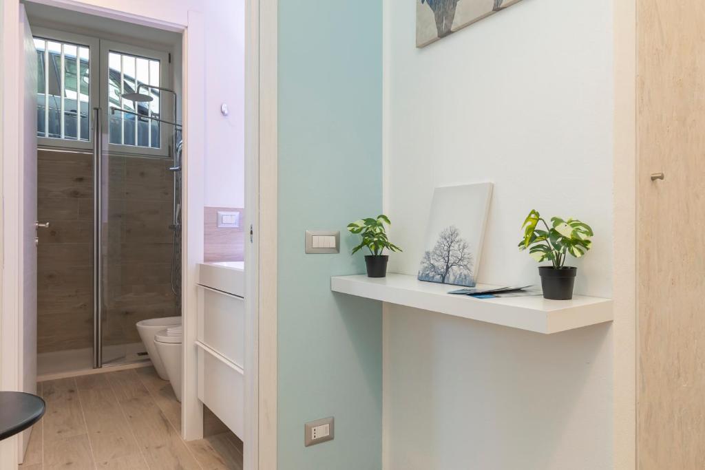 łazienka z toaletą i roślinami na półce w obiekcie [Sweet apartment] - Grazioli 2 w Mediolanie