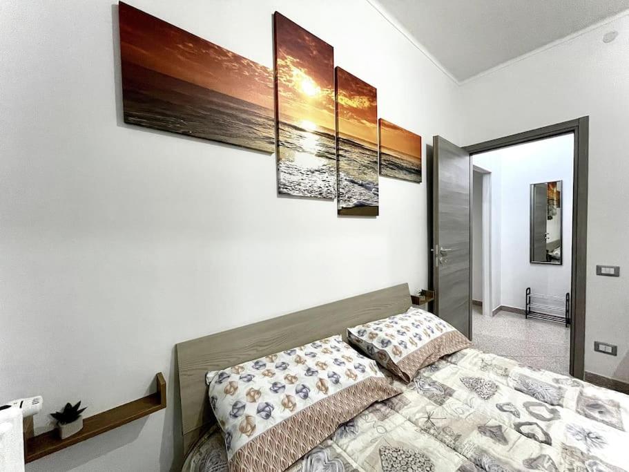 a bedroom with a bed with four paintings on the wall at Comodo Bilocale in ottima posizione in Alessandria
