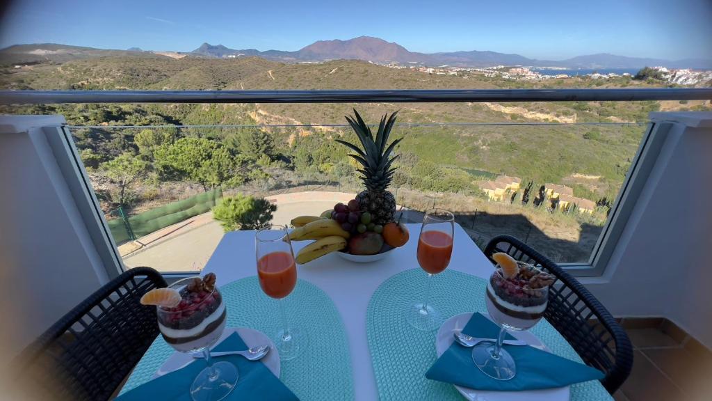 uma mesa com uma taça de fruta e bebidas em Lovely apartment with a breathtaking panoramic view of the mountains and the sea,FIRST LINE!! em Manilva