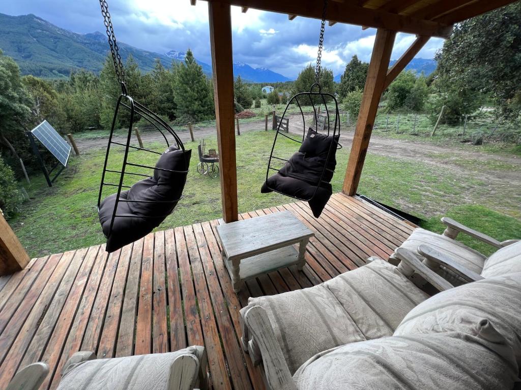 dos columpios en una terraza con sillas y una mesa en Cabaña Meliquina en Villa Meliquina