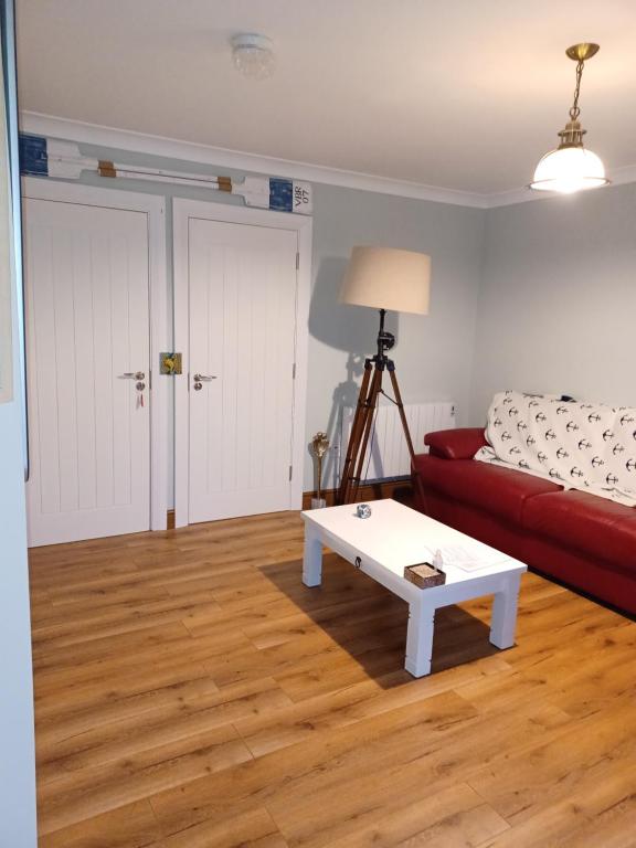 Sala de estar con sofá rojo y mesa de centro en The Boathouse, en Cork
