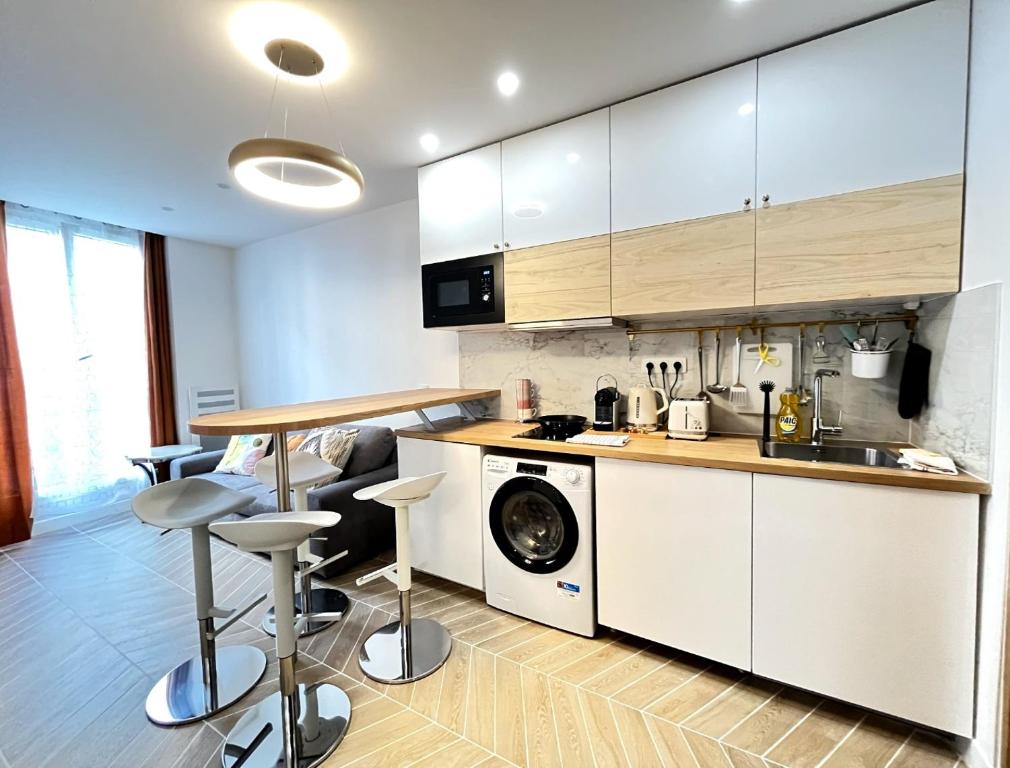 une cuisine avec des armoires blanches et une laveuse et une sécheuse dans l'établissement New Inn Paris, à Paris