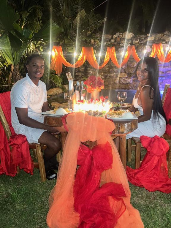 a man and a woman sitting at a table with food at CHALET TROPICAL Hotel & Restaurant-Pizzeria in Las Galeras