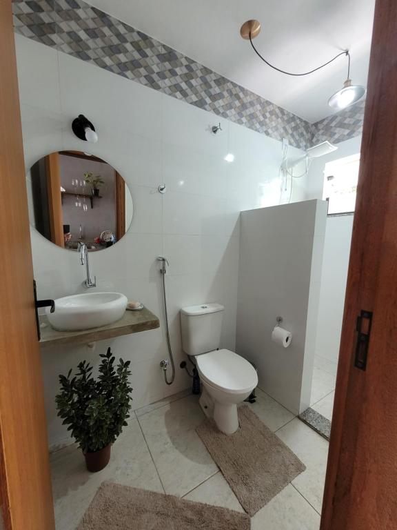a bathroom with a toilet and a sink and a mirror at Estância Shangri-La in Santa Teresa