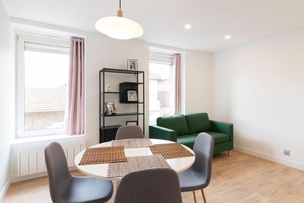 a living room with a table and a green couch at LE 23 in Jarny