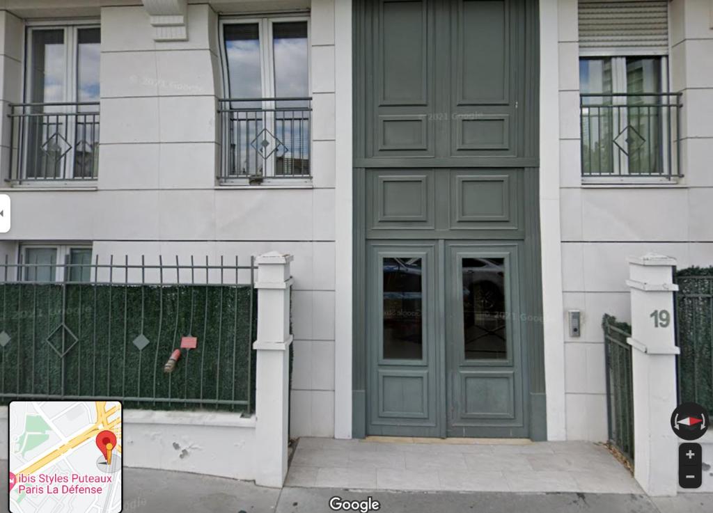 a green door on a white building with a fence at Moderne & LUXURY T2 Paris la défense in Puteaux