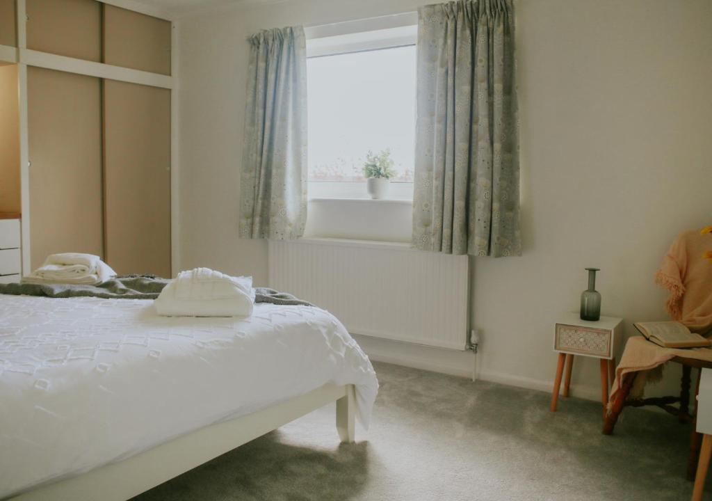 DonVera - Two Bedroom Bungalow with Sea Views في Overcombe: غرفة نوم بسرير ابيض ونافذة
