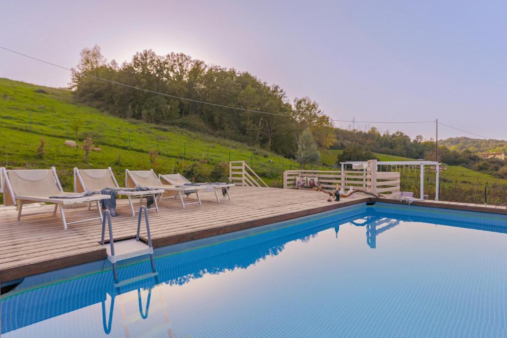 una terraza de madera con sillas y una piscina en Villa Siveri - private swimming pool - air con, en Figline Valdarno