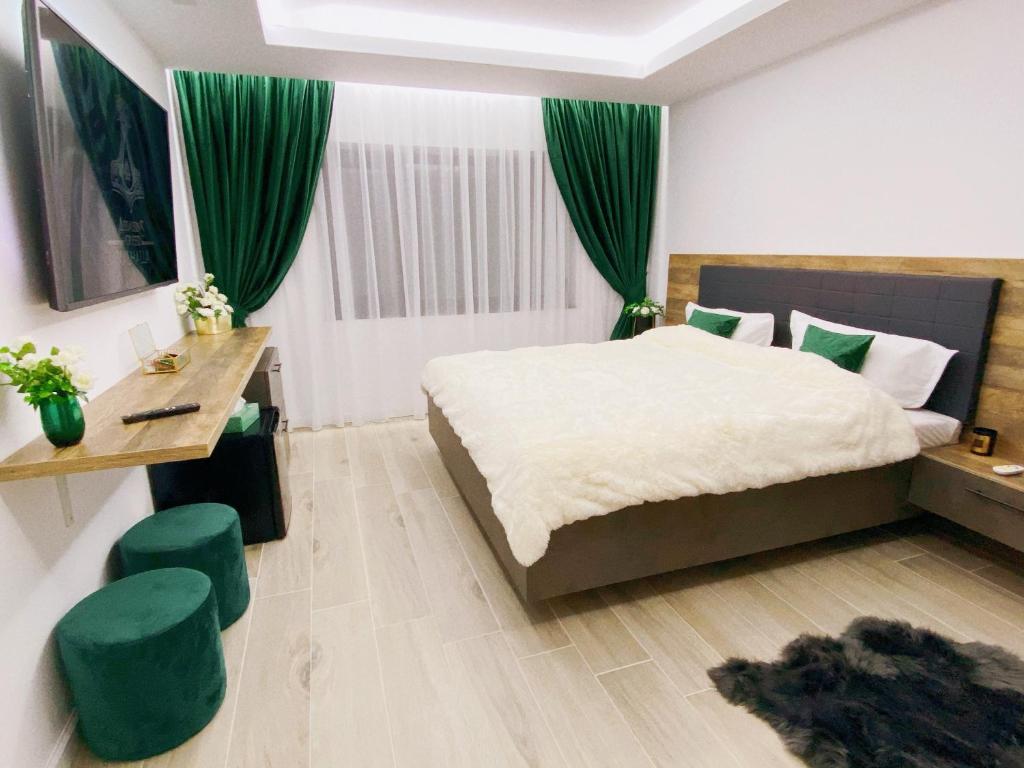 a bedroom with a large bed with green curtains at Villa Virginia in Broşteni