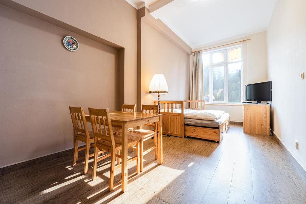 a dining room with a table and chairs and a bed at Apartmány Pod Kolonádou in Janske Lazne