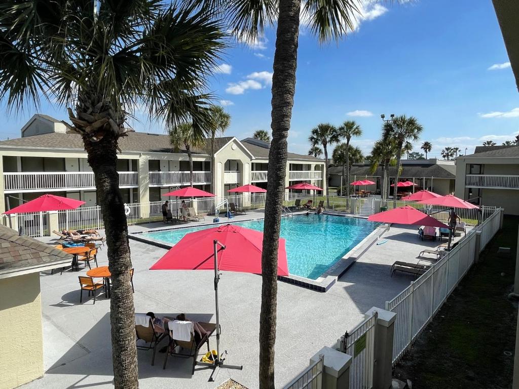 una piscina con sombrillas rojas y un complejo en Newly Room in cozy hotel with Super location to the Parks, en Kissimmee