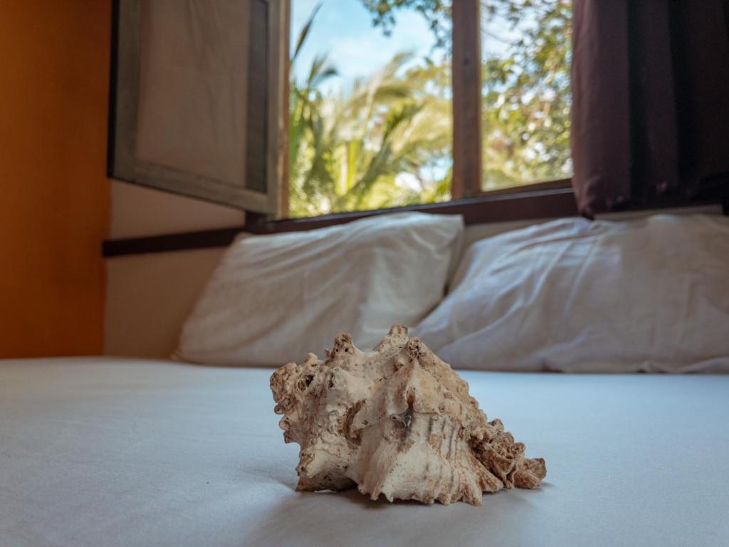 a rock sitting on top of a bed with a window at Uvita River Guesthouse in Uvita