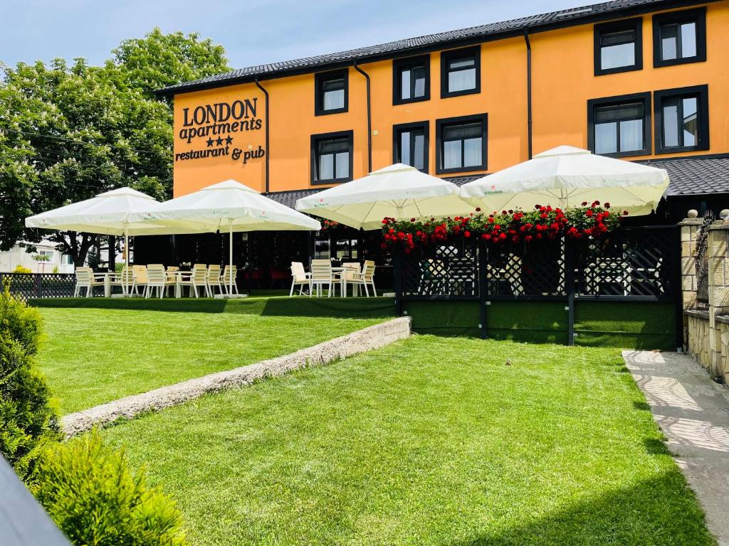 a hotel with tables and umbrellas in a yard at London Apartments Vaslui in Vaslui