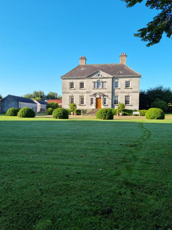 a large white house with a large grass field at Summergrove House in Mountmellick