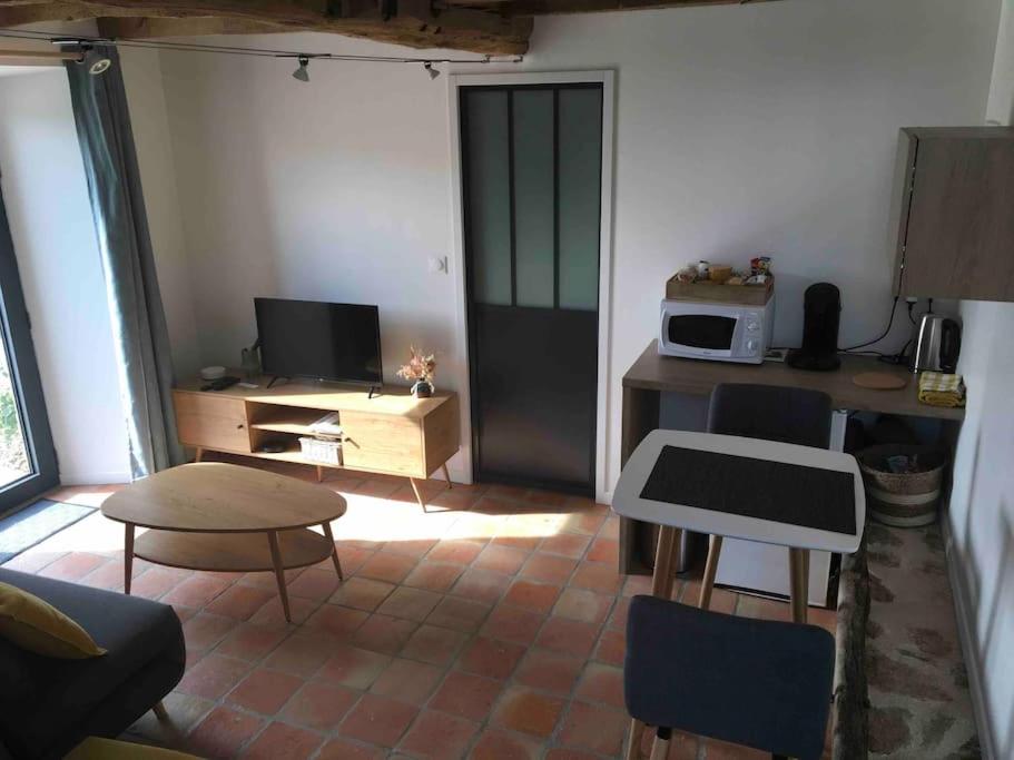 a living room with a table and a microwave at Logement agréable à la campagne in Saint-Symphorien