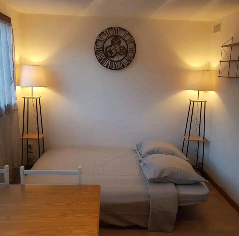 een slaapkamer met een bed en een klok aan de muur bij Superbe studio dans la vallée de l'Eau d'Olle. in Allemont