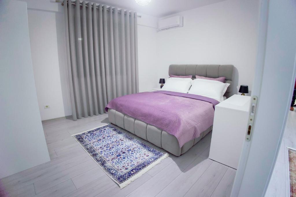 ein Schlafzimmer mit einem Bett mit einer lila Decke und einem Teppich in der Unterkunft GRANDE APARTMENT KORCE in Korçë