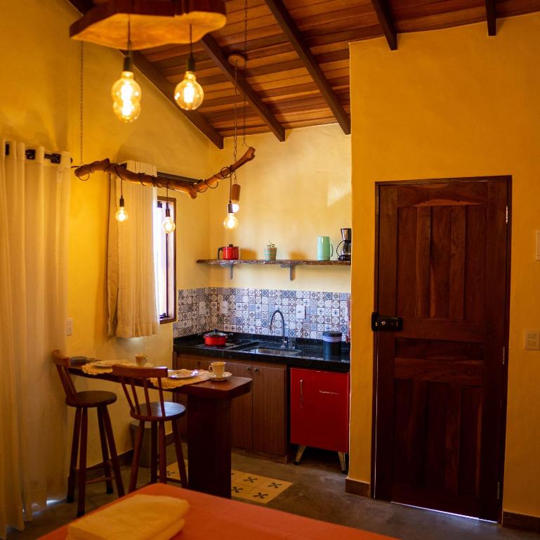 a kitchen with yellow walls and a table and a counter at Espaço Canela-de-Ema in Alto Paraíso de Goiás