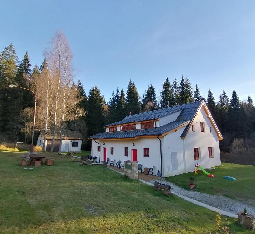 ein weißes Haus mit roten Türen auf einem Grasfeld in der Unterkunft Apartmány Na samotě in Kubohütten