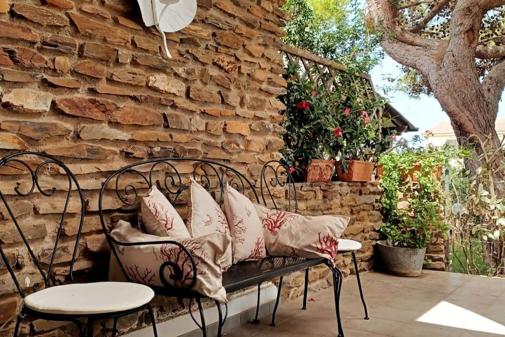 a bench with pillows on a patio with a stone wall at Villa Fronte Mare in Stintino