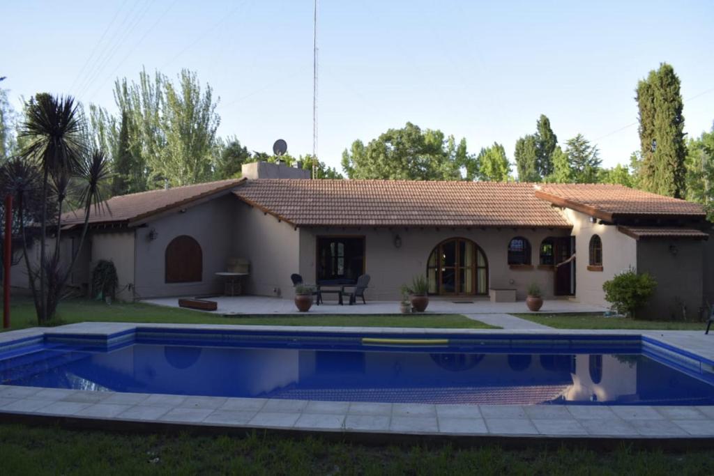 a villa with a swimming pool in front of a house at Como en casa in Chacras de Coria