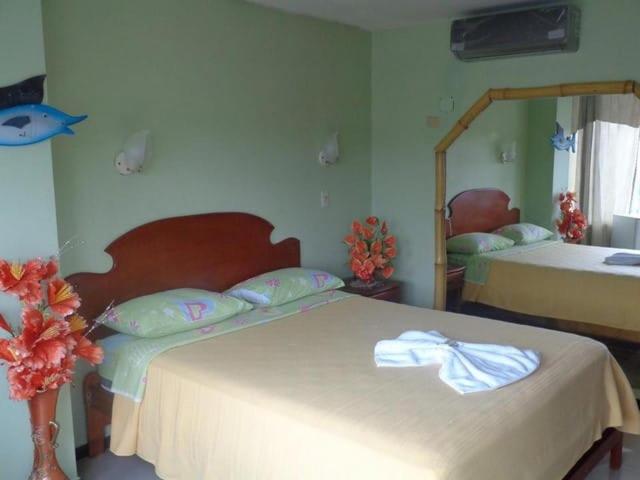 1 dormitorio con 2 camas y espejo en Hostal BAMBU, en Tena