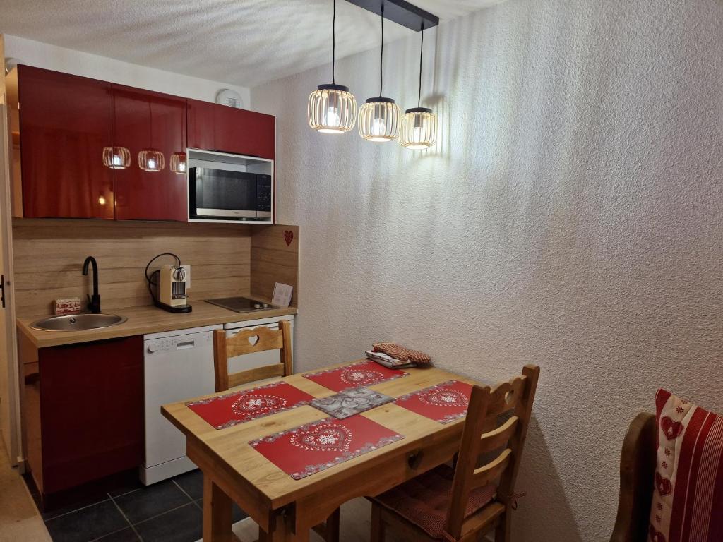 a kitchen with a wooden table and a kitchen with red cabinets at 2 pièce cabine Val Thorens in Val Thorens