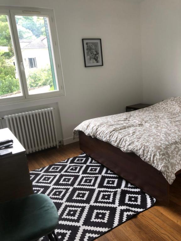 1 dormitorio con cama, alfombra y ventana en Appartement paisible proche centre ville, en Villennes-sur-Seine